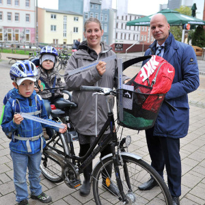 Senator Dr. Chris Müller übergab Stefanie Labitzke und ihren Kindern Max und Hannes Leuchtbänder mit der Aufschrift „Rostock lässt sich sehen“. Foto: Joachim Kloock