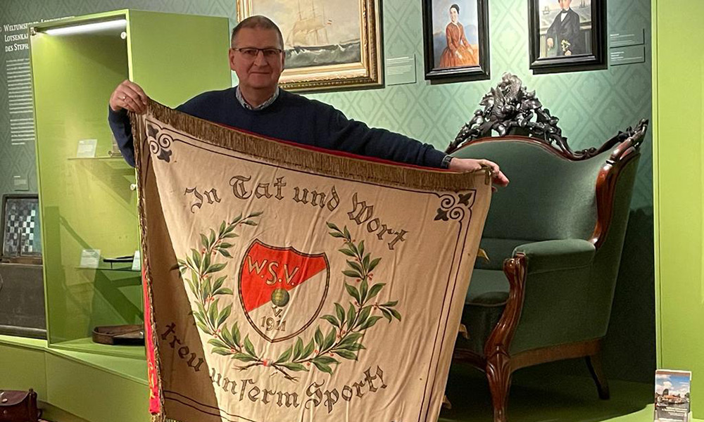 Uwe Heimhardt vom Heimatmuseum zeigt die Fahne des Warnemünder Sportvereins 1911